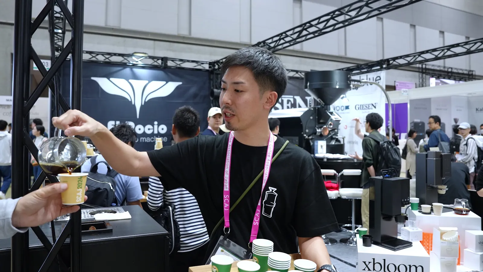 SCAJ 2024 도쿄 전시장 — 부스에서 커피를 건네는 바리스타